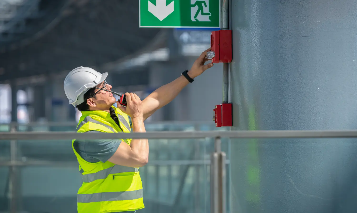 Ingenieur trägt Sicherheitsuniform und Helm und überprüft den Feueralarm